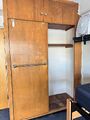 A wooden closet with the door aside. The interior is a large open space with a bar running across
